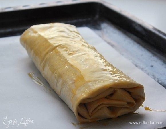 Рулет выложить на лист пергамента или силиконовый коврик. Смазать желтком. Поставить в заранее нагретый до 180°С духовой шкаф на 20 минут до зарумянивая.