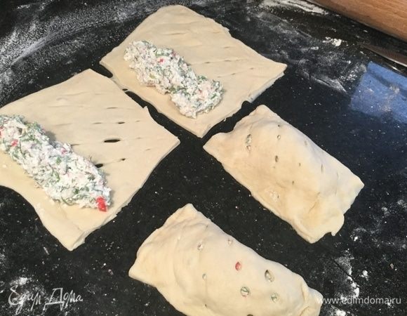 На вторую половину квадрата выложите начинку, закройте пирожок той стороной, которая с надрезами и защипните края.