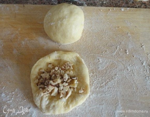 Каждый кусочек расплющите руками, на середину положите чайную ложку начинки, защипните края и скатайте в шарики.