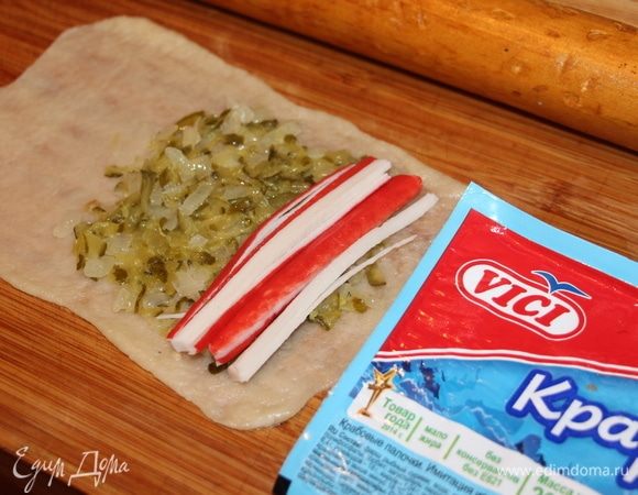 Раскатать шарики теста в очень  тонкий, почти прозрачный пласт (тесто раскатывается очень легко). Кладем начинку из огурцов, поверх кладем нарезанные соломкой крабовые палочки ТМ «VICI» , они сочные и очень нежные и прекрасно будут сочетаться с начинкой из соленых огурцов.