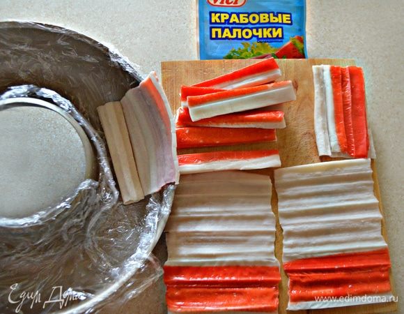 Крабовые палочки Vici аккуратно развернуть. Красную часть отделить и выложить ею стенки формы. Белую часть мелко нарезать.