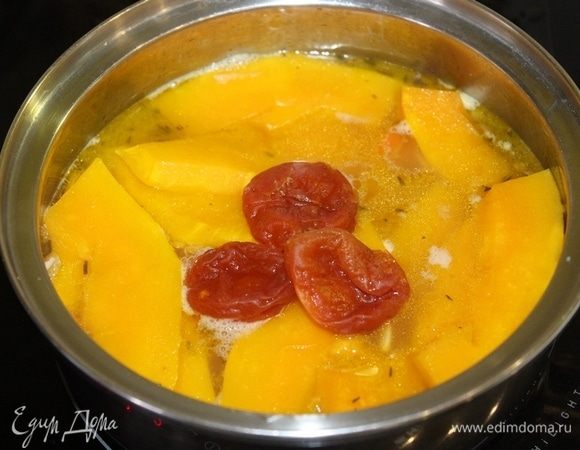 В кастрюлю к обжаренным овощам добавьте овощной бульон и варите, пока морковь не станет мягкой. Затем добавьте тыкву и курагу и варите еще 10-15 минут.
