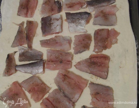 Смазываем лист маслом. Переносим на него пласт теста. Укладываем, предварительно посолив по-вкусу, рыбу на тесто.