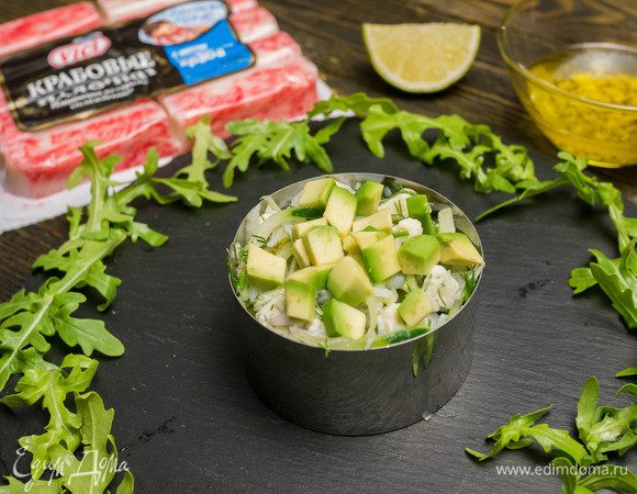 Выкладываем салат в порционную тарелку или форму, а сверху кладем нарезанное кубиками авокадо.