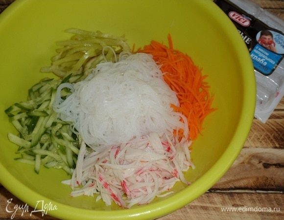 Выкладываем в глубокую чашку нарезанные овощи и подготовленную фунчозу. Добавляем крабовые палочки ТМ VICI с мясом натурального краба, разобрав их на волокна.