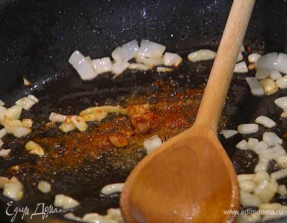 В сковороду, где жарились баклажаны, влить оставшееся оливковое масло, выложить лук и чеснок, добавить паприку, зиру, орегано и перец чили, все перемешать и обжарить.