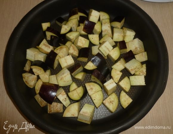 Разогреть духовку до 180°С. Баклажан и лук нарезать небольшими кусочками, сложить в форму для запекания. 