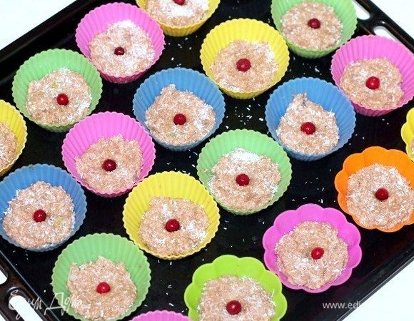 Формируем печенье. Можно выложить на противень, застеленный пергаментной бумагой. Или как у меня, выложить по 1 столовой ложке в силиконовые формочки. Посыпать заготовки кокосовой стружкой и украсить ягодами.

