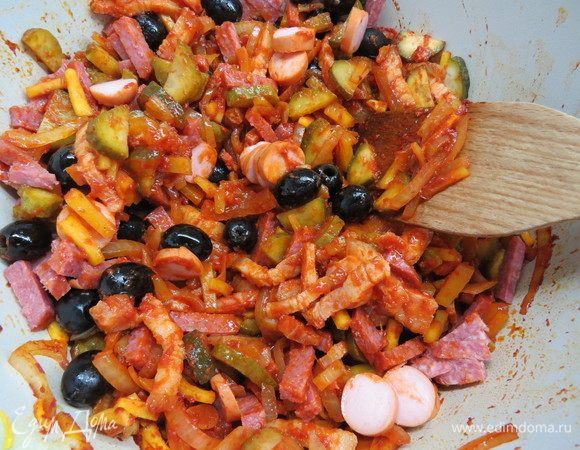 В основной казан добавляем маслины без косточек, нарезанную полосками варено-копченую колбасу и сосиску, также добавляем обжаренное мясо со второй сковороды.