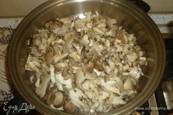Грибы нарезать. Пока варится рис, разогреть в большом сотейнике масло. Выложить грибы и жарить, помешивая, до испарения жидкости.