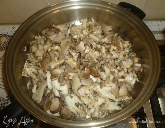 Грибы нарезать. Пока варится рис, разогреть в большом сотейнике масло. Выложить грибы и жарить, помешивая, до испарения жидкости.