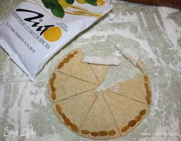 Разделить вырезанный круг на 8 частей. По краю выложить изюм (по желанию можно заменить орехами). Завернуть к середине (см. фото). 