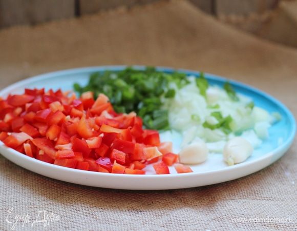 Бекон, перцы, сельдерей, лук и обесшкуренные помидоры нарезать кубиками, чеснок пропустить через давилку. В большой кастрюле, желательно с толстым дном, разогреть масло и положить бекон. Выжарить его на среднем огне до золотистого цвета. Положить в кастрюлю перец, лук и сельдерей, после чего обжаривать 3–5 минут до прозрачности лука. Добавить чеснок и обжарить все еще минуту.