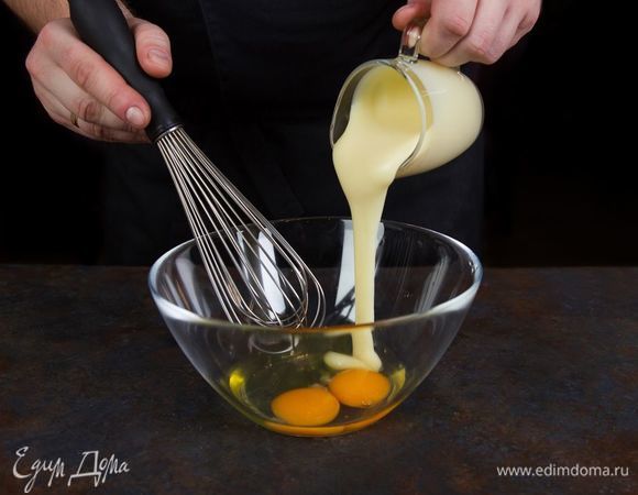 Приготовьте тесто для шарлотки. Для этого взбейте сгущенное молоко с яйцами. 