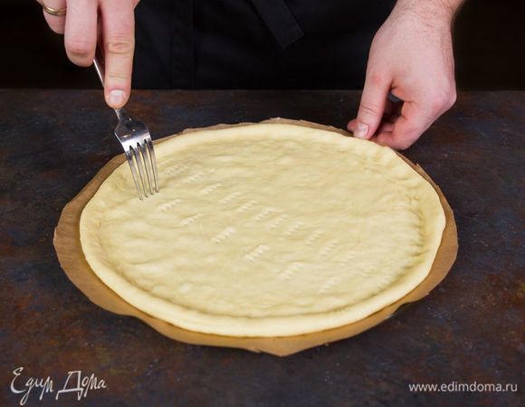 Плоское блюдо для микроволновки посыпьте мукой и на нем раскатайте тесто в тонкий пласт. Проткните тесто вилкой в нескольких местах.
