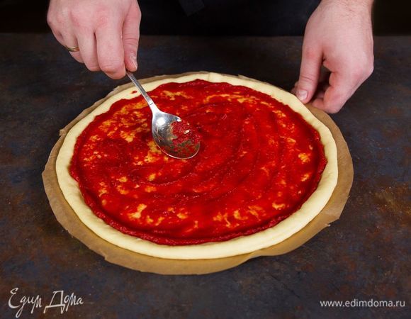 Смажьте тесто томатной пастой.