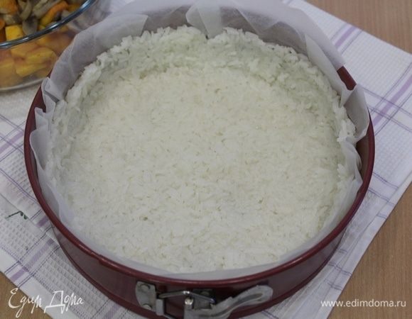 Рис уложите в форму, выложенную бумагой для выпечки, утрамбуйте по дну и бортикам формы.