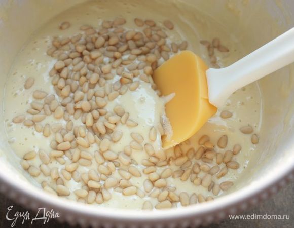 Всыпьте в тесто половину орешков и перемешайте, чтобы равномерно их распределить.