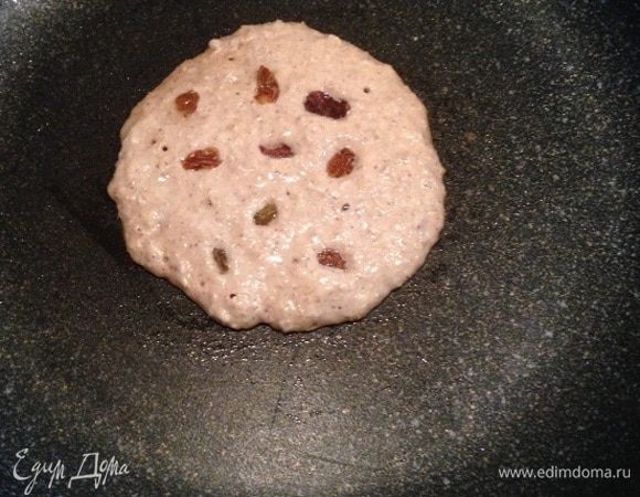 Сковороду слегка смазать растительным маслом. Выложить 2 ст. л. теста и выпекать на среднем огне примерно 5 минут (просто следите за готовностью и, когда необходимо, переверните). Пока готовится с одной стороны, равномерно выложите изюм. Затем переверните и выпекайте ещё столько же по времени.