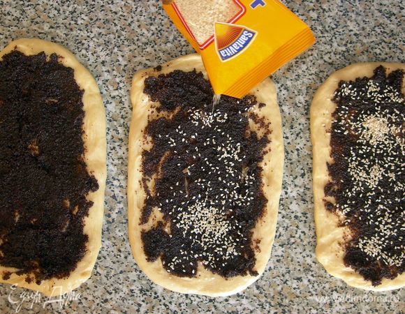 Сверху  маковой начинки на каждую из заготовок можно, по желанию, посыпать орешки, кунжут, изюм или нарезанную курагу (на ваше усмотрение). Я посыпала только кунжутом. Мне попался крупный, чистый и вкусный.