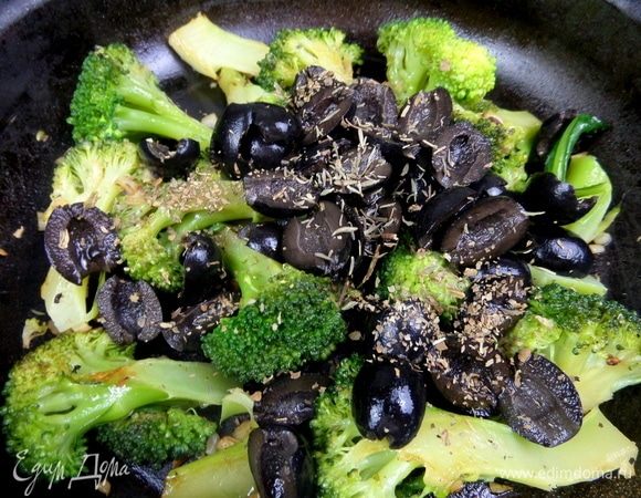 Пересыпать маслины в сковороду, добавить кусочек сливочного масла, тимьян и базилик. Влить пару ложек отвара от капусты.