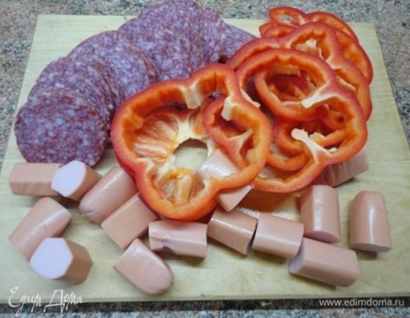 Салями нарезать колечками, перец — кружочками, а сосиски — на кусочки примерно 2,5–3 см.