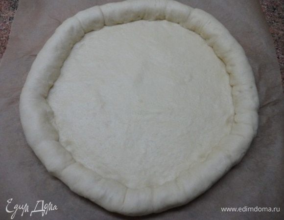 Сосиски завернуть в тесто, защипав края. Пиццу вместе с бумагой переместить на противень. 