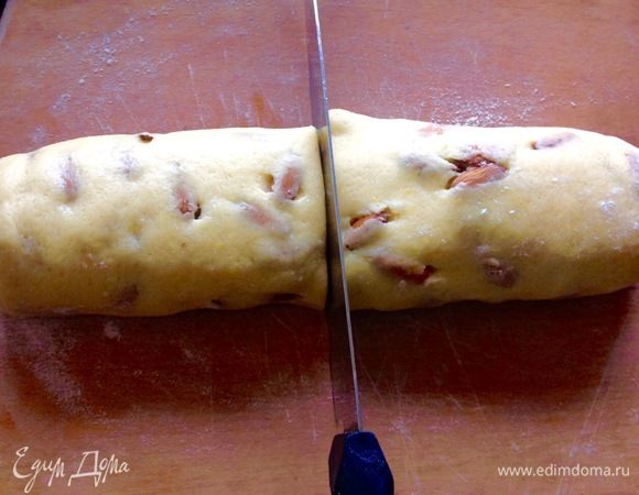 Готовый ком теста уже с миндалем скатываем в толстую колбасу и разрезаем ее пополам.