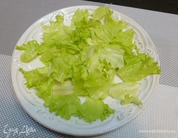 На сервировочной тарелке собираем салат. Листья салата порвем крупными кусками и разложим на тарелке.