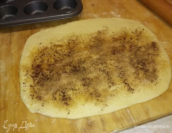 Раскатать тесто в прямоугольник. Смазать его сливочным маслом, не доходя до одного края 3–4 см.
Посыпать сахаром и ванильным сахаром, корицей. Свернуть в рулет и разрезать на 12 частей.