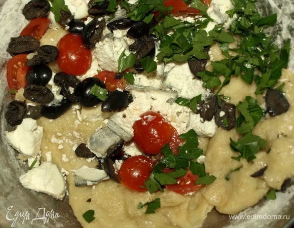 Разрезаем 6 помидоров черри на две половинки (остальные 6 шт. пойдут на украшение). Козий сыр (у меня серый козий сыр) режем на кусочки (можно заменить фетой). Маслины разрезаем на несколько частей. Петрушку мелко рубим. Все продукты добавляем к тесту. Соль и перец по вкусу.