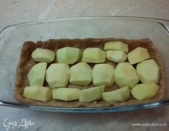 Песочное тесто выложить в форму. Сформировать бортики. Яблоки очистить от сердцевины и кожуры. Разрезать на четвертинки и уложить на песочную основу.