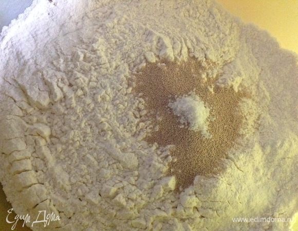 В другую миску просеваем муку, добавляем сухие дрожжи и щепотку соли.