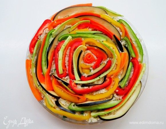 По окружности выложить овощи, вдавливая их в фарш по всей поверхности запеканки разноцветными кольцами.