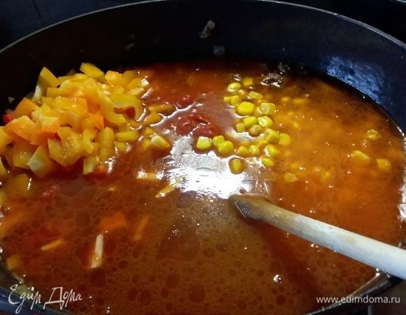 Влить вино, увеличить огонь и дать выпариться алкоголю. Влить бульон, добавить помидоры (предварительно их измельчить), маис, кубики перца, размешать. Тушить на медленном огне 15 минут. 