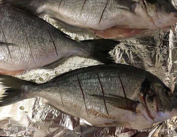 Укладываем рыбу на противень, делаем надрезы и смазываем верх оливковым маслом.