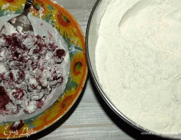 Вишню заранее разморозить, дать стечь жидкости. Муку просеять с разрыхлителем, добавить щепотку соли. В вишню добавить пару ложек муки и перемешать.