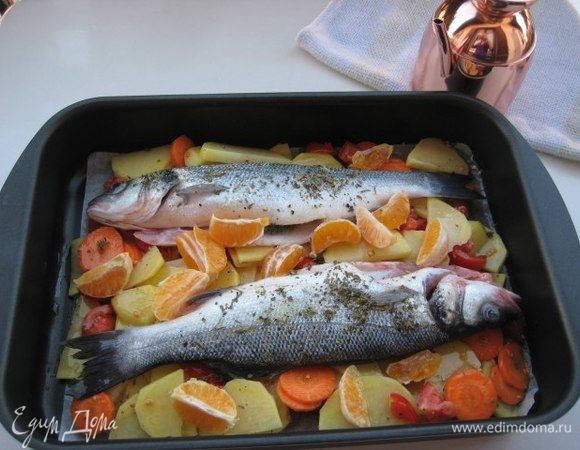 Форму для запекания смазать оливковым маслом, выложить овощи, сверху рыбу. Рыбу сбрызнуть оставшимся оливковым маслом, влить сухое белое вино. Запекать при температуре 180°С около 30 минут до готовности блюда.