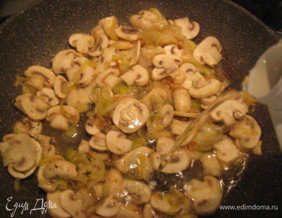 Влить белое вино, перемешать, готовить на небольшом огне около 10 минут до готовности лука и грибов.