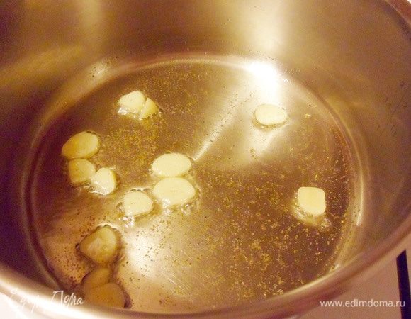 Приступить к приготовлению соуса: в кастрюлю с толстым дном налить оставшееся оливковое масло. Выложить чеснок, добавить щепотку молотого кориандра и жарить в течение 2 минут.