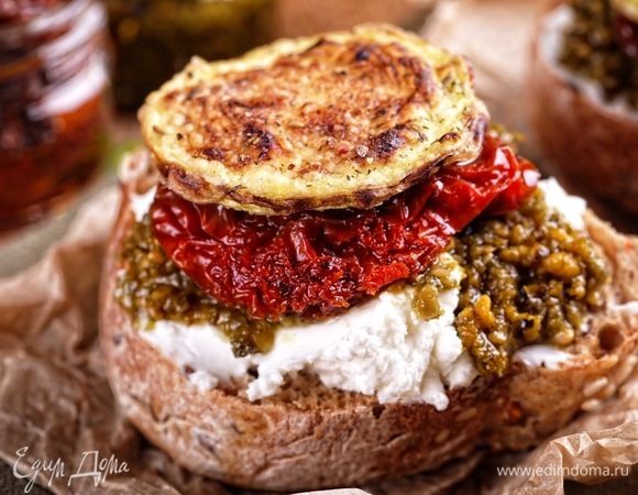 Остается только подключить фантазию и собрать вот такой маленький бутербродик: ломтики багета смазать оливковым маслом и подсушить на сухой сковороде, сверху выложить по 1 ст. л. творожного сыра, на него — ломтик вяленого помидора, на него — столовую ложку свежего песто (у меня покупной) и закончить эту башенку ломтиком хрустящего кабачка! Подавать немедленно к вину или просто так:) Это очень вкусно!