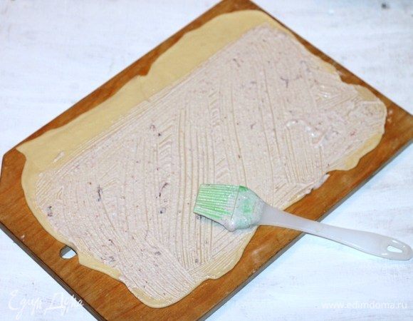 Две части теста раскатываем в пласт, формируем прямоугольник равный 25х33. Смазываем прямоугольник растопленным сливочным маслом и затем начинкой. 