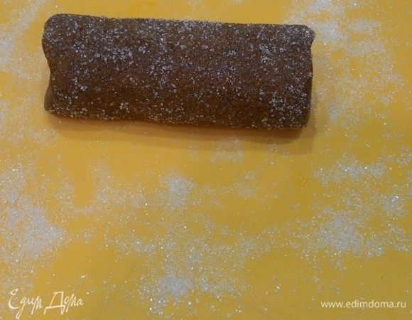 Разогрейте духовку до 180°С. В маленькой миске взбейте яичный желток, чтобы он стал гладим и жидким. В дальнейшем используем его в качестве глазури. Распределите немного сахара на доске. Извлеките колбаски из холодильника, освободите от пищевой пленки и смажьте, помощью кисточки глазурью. Обваляйте колбаски в сахаре.