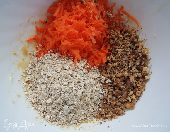 Морковь натереть на крупной терке, грецкие орехи мелко нарезать. 
Добавляем морковь, орехи и овсяные хлопья к масляно-яичной смеси, перемешиваем.