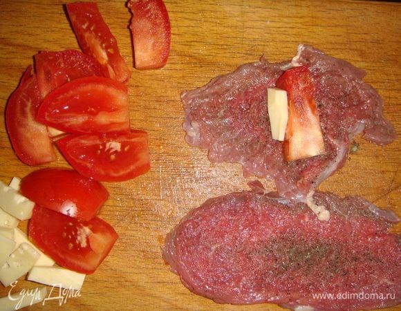 Отбить, посолить и поперчить по вкусу. Помидор и сыр нарезать брусочками. Положить на один край мяса по одному брусочку помидора и сыра, свернуть в рулетик.