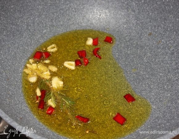 На разогретую глубокую сковороду влить 6 ложек олвкового масла Extra Virgin, порубить тонкими кружками 1,5 зубчика чеснока, 3 пеперончино и 1 веточку розмарина. На медленном огне довести специи до светло-коричневого цвета, выловить их с помощью шумовки, выкинуть. Выключить огонь, отставить в сторону.