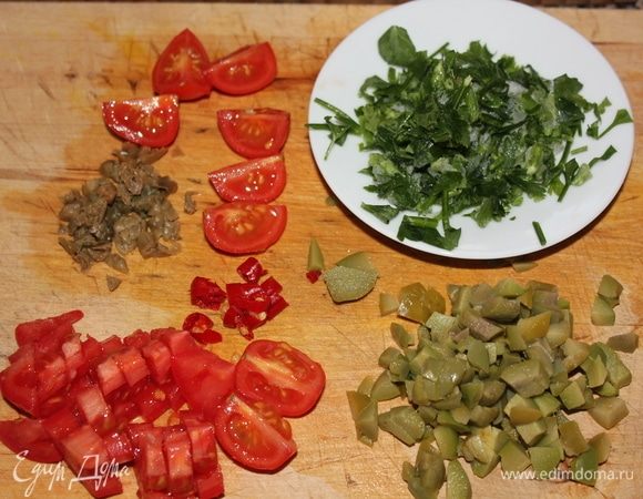 Как закипела вода, закинуть в кастрюлю спагетти и варить 9,5 минут. Тем временем подготовим каперсы, промытые под проточной водой от соли. Мелко нарезать каперсы, пеперончино, свежую петрушку (у меня была свежемороженая), оливы и помидоры черри. Черри достаточно разрезать на 4 части.