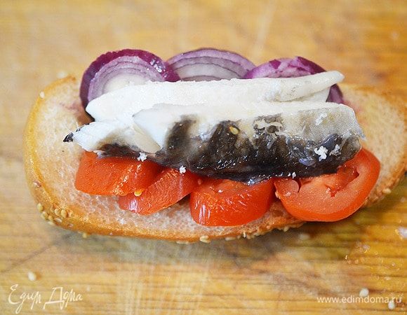 В булочку выложить кольца помидора, лука и запеченное филе рыбы.