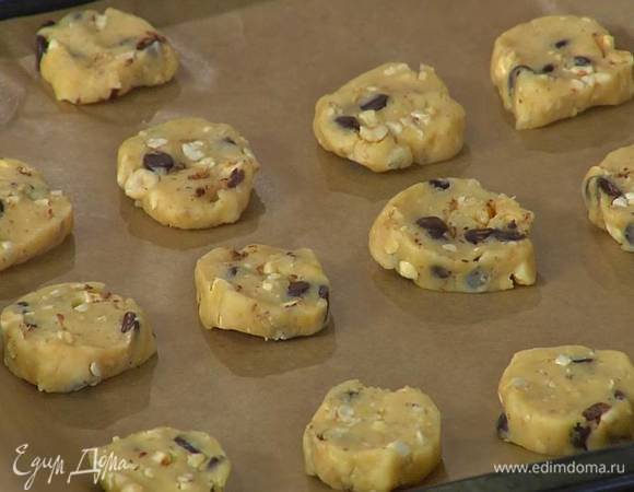 В тесто добавить орехи и шоколад, сформировать из теста поленце, нарезать кружками толщиной в 1 см и выложить их на противень, выстеленный бумагой для выпечки.