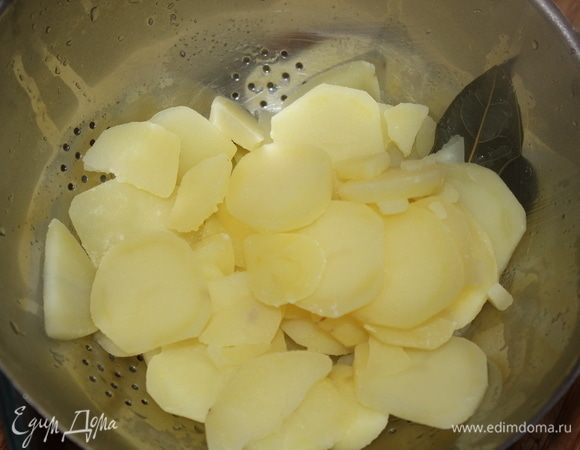 Выложить отваренный картофель в дуршлаг, дать стечь полностью воде, выбросить лавровый лист. Включить духовку, установить термометр на отметку 180°C.